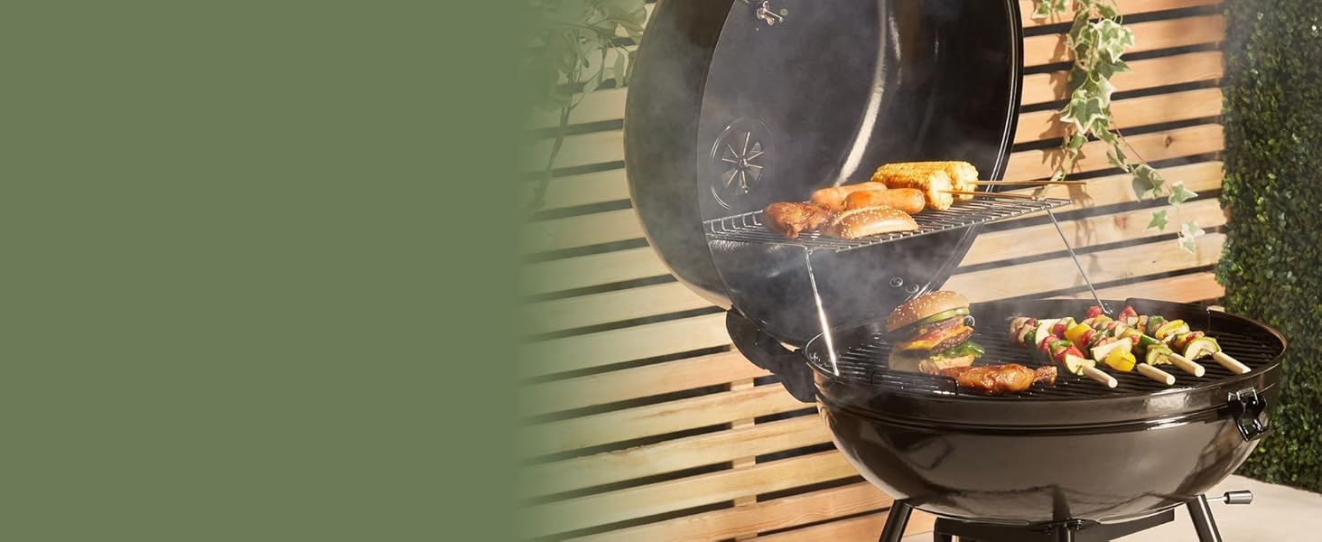 avec couvercle ouvert, cuisson des brochettes et des légumes sur des grilles. De la fumée s'élève, ce qui indique que le processus de cuisson