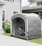 Abri de rangement à vélos portable gris avec toile de fond de maison en brique blanche, avec porte à ouverture avant et panneaux de ventilation pour un rangement sécurisé des vélos.