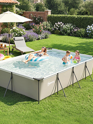 Piscine hors sol rectangulaire avec pieds à ossature métallique positionnés sur une pelouse verte. La piscine contient de l'eau et plusieurs enfants nagent et jouent. Arrière-cour résidentielle avec jardin, haies et chaises longues visibles.