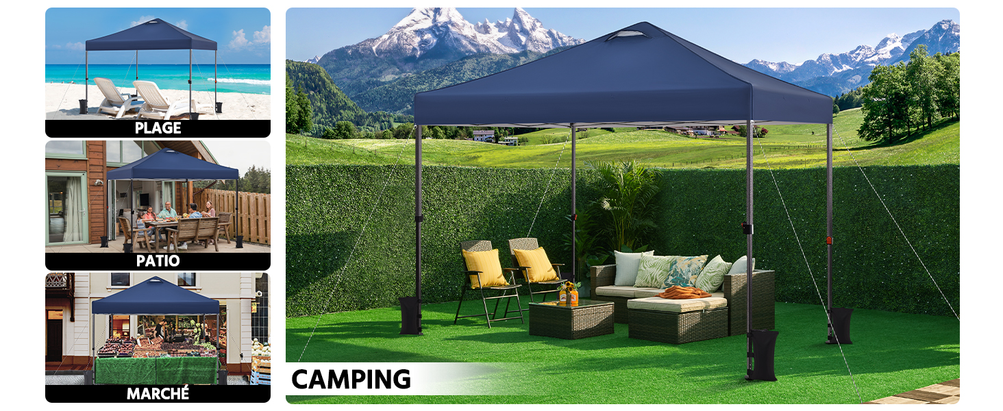 Grande tente extérieure à baldaquin avec dessus en tissu bleu foncé, installée sur de l'herbe verte. Meubles de patio, y compris des chaises et un canapé visibles en dessous. Montagnes enneigées en arrière-plan.