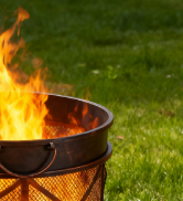 Série d'images montrant un foyer ou un récipient de cuisine extérieur avec des flammes visibles dans un environnement extérieur gazonné en soirée ou au crépuscule.
