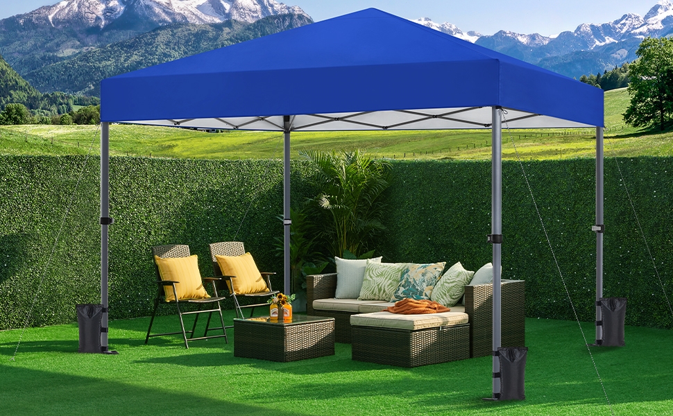 installée sur l'herbe, recouvrant le mobilier d'extérieur, y compris un canapé en osier, des chaises et une table. Les montagnes sont visibles en arrière-plan.