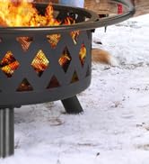 avec découpes en forme de losange, flammes ardentes visibles à travers les ouvertures. Construction métallique avec pieds, posée sur un sol enneigé.
