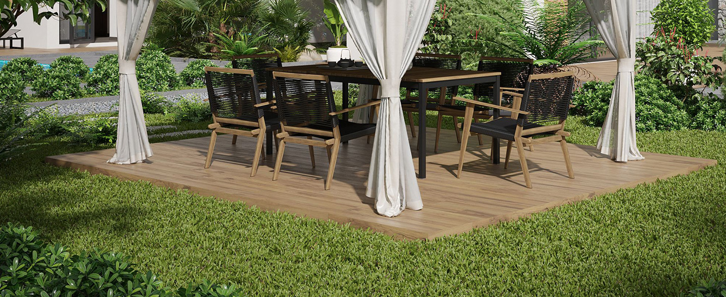 Terrasse extérieure en bois avec deux tables et chaises carrées, entourées de rideaux blancs. Situé dans un jardin luxuriant avec de l'herbe verte et des arbres.