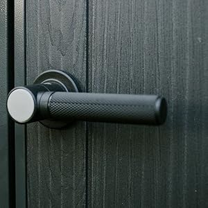 Porte ou panneau en métal gris de style industriel avec motif de nervures verticales, mettant en valeur les détails architecturaux dans des conditions de faible éclairage.
