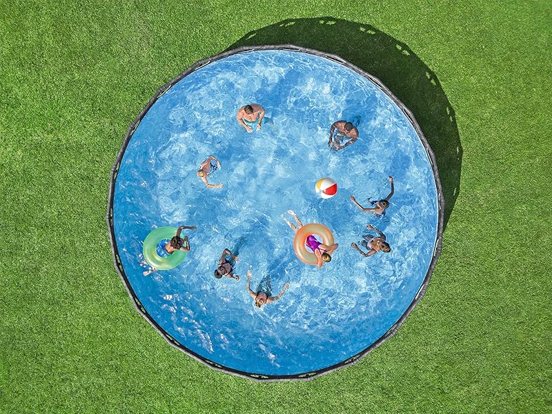 Piscine hors sol circulaire sur gazon, remplie d'eau bleue. Plusieurs personnes nagent et flottent sur des structures gonflables colorées à l'intérieur de la