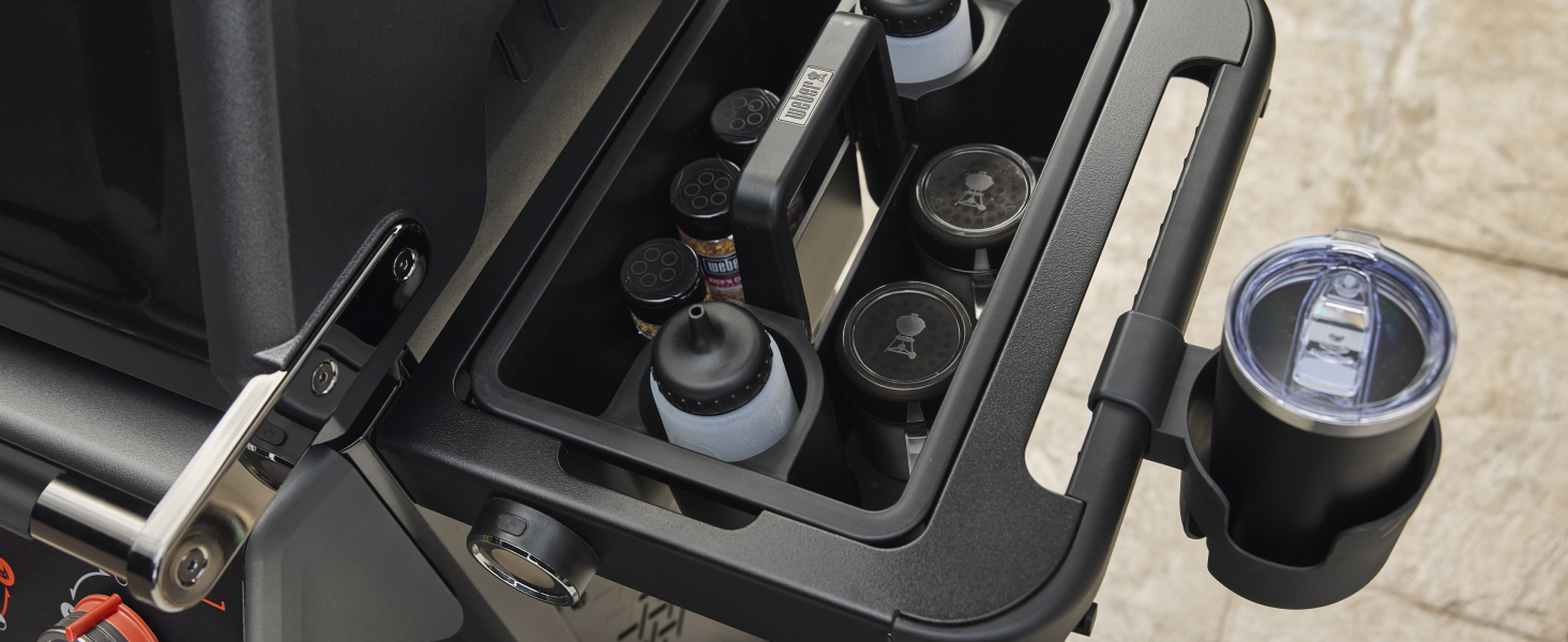 Vue rapprochée de ce qui semble être la console centrale ou le compartiment de rangement d'un véhicule avec des surfaces sombres et de multiples compartiments visibles.