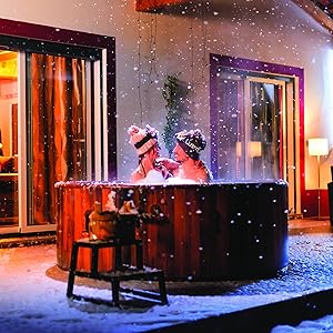 Scène de bain à remous extérieur la nuit. Baignoire en bois avec deux occupants, environnement enneigé, éclairage chaleureux provenant du bâtiment voisin