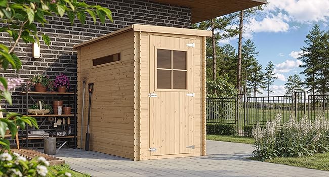 Petit abri de jardin en bois avec toit en pente et fenêtre unique, placé sur un patio près d'un mur de briques. Entouré de plantes et de mobilier d'extérieur dans le jardin.