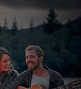un couple assis sur un banc en train de jouer de la guitare