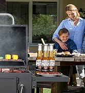 Scène de grillades en plein air avec barbecue fumant et bouteilles de sauce sur une table d'appoint. Cuisson visible des aliments sur les grilles du gril
