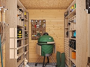 Intérieur du hangar de rangement en bois organisé avec des étagères des deux côtés, abritant divers outils et équipements. Un grand grill ou un fumoir vert en forme d'œuf est placé au centre à l'arrière