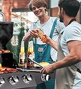 avec deux personnes en train de cuisiner. Bouteilles sur la table d'appoint du grill. Une personne tient un aliment au-dessus du gril.