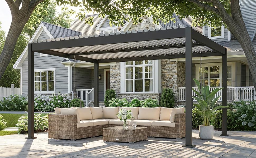 Pergola moderne avec toit à lattes recouvrant le coin salon extérieur et dotée de meubles sectionnels rembourrés beiges. Une maison de style artisanal en pierre et en bois est visible en arrière-plan.