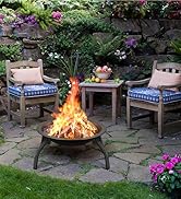 Cadre de patio extérieur avec fond de mur en pierre, deux chaises en bois avec coussins bleus, une petite table et un foyer actif, entouré de fleurs de jardin colorées.