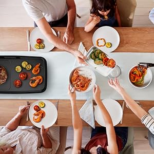 Série de plans aériens montrant des mains préparant et étalant des plats colorés sur des assiettes blanches sur une surface en bois.