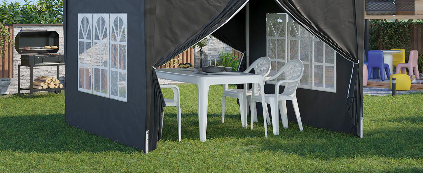 Tente extérieure à baldaquin de couleur foncée avec panneaux latéraux, contenant une table et des chaises en plastique blanc. La tente a des panneaux de fenêtre transparents et est installée sur l'herbe.