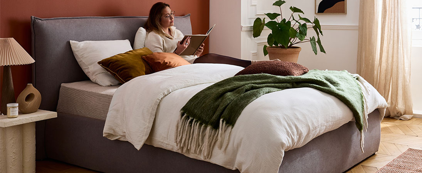 L'intérieur de la chambre moderne comprend un lit bien fait avec une literie grise et un décor minimaliste.