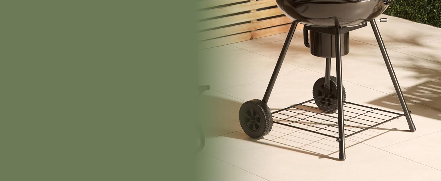 Vue partielle d'un grill extérieur noir ou d'un barbecue sur roues avec un corps rond de style bouilloire et des