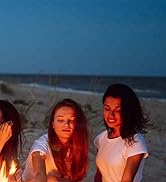 Trois femmes assises autour d'un feu de camp sur la plage