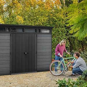 Vues multiples d'une grande unité de rangement extérieure gris foncé ou d'un cabanon dans un jardin avec de la verdure visible en arrière-plan.