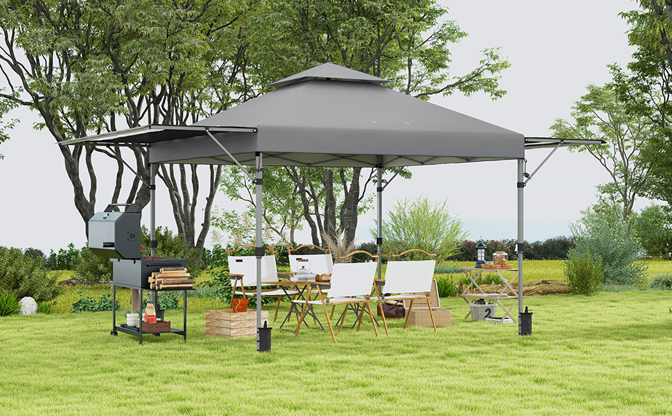 Grande tente extérieure à baldaquin avec housse en tissu gris. Installé dans le jardin avec des chaises, une table et un grill en dessous. Arbres en arrière-plan.