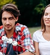 un jeune couple est assis dans le parc et mange des guimauves