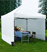 Tente à baldaquin escamotable blanche installée sur l'herbe, avec parois latérales. L'intérieur montre une table pliante avec un tissu à carreaux, des chaises et une salle à manger extérieure.