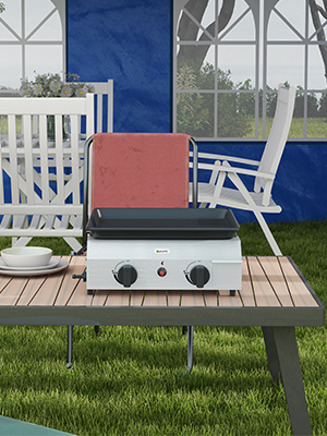 Installation de cuisine extérieure avec une grille rectangulaire blanche sur une table en bois. Des fauteuils à bascule blancs sont visibles en arrière-plan.