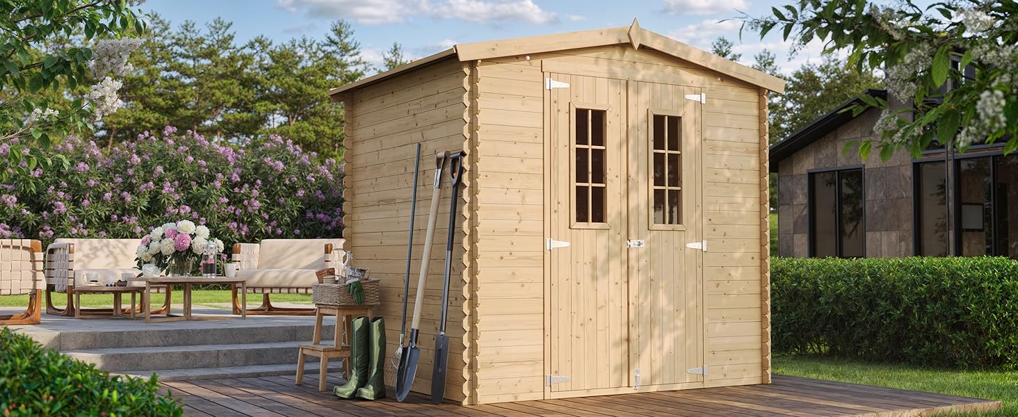avec toit en pente et portes doubles, situé sur un patio. Les outils de jardin sont appuyés contre le côté. Aménagement paysager environnant visible.