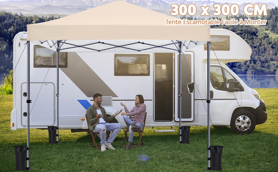 Grand auvent beige fixé sur le côté du camping-car blanc. Deux personnes assises sous un auvent. Texte « 300 x 300 CM » visible. Lac pittoresque et fond de montagne.