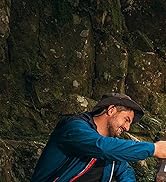 Personne en veste bleue et casquette utilisant un appareil portatif sur une surface rocheuse à l'extérieur. L'appareil semble être un outil de nettoyage ou de maintenance.