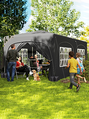 Grande structure gonflable ou temporaire noire installée sur une pelouse verte, avec des personnes qui s'y déplacent en extérieur.