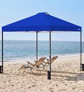 sur une plage, fournissant de l'ombre à deux chaises longues pliantes. La tente a une forme carrée avec des pieds inclinés et est ancrée à l'aide