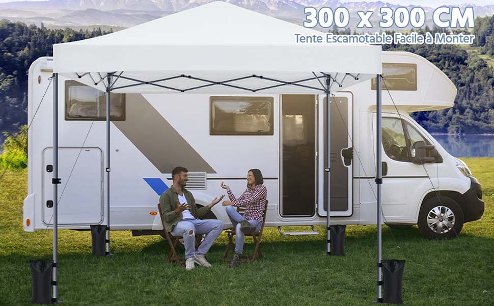 de 300 x 300 cm attaché à un camping-car. Deux personnes assises sous la canopée étendue. Lac pittoresque et toile de fond montagneuse.