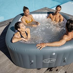 Spa gonflable sur une terrasse en bois. Quatre personnes se détendent dans une eau bouillonnante. Extérieur gris avec sièges intégrés pour plus de confort et de convivialité.