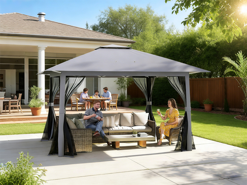 Grand belvédère extérieur avec auvent gris installé sur la terrasse. Comprend des panneaux latéraux en maille et contient un ensemble de meubles d'extérieur avec des sièges rembourrés en dessous.