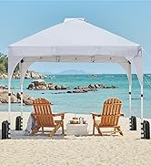 Tente à baldaquin escamotable blanche sur la plage avec deux chaises Adirondack en bois en dessous. La tente a des pieds inclinés avec des poids. L'océan et la côte rocheuse sont visibles en arrière-plan.