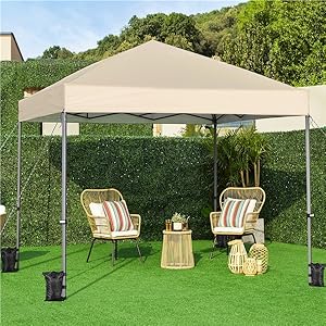 installée sur l'herbe, avec deux chaises en osier et une petite table en dessous. Une haie et des arbres sont visibles en arrière-plan.