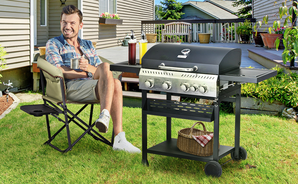 Grand barbecue extérieur à gaz avec brûleurs multiples et étagères latérales sur une terrasse. Chaise pliante et plantes visibles à proximité.