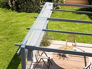 avec auvent rétractable en tissu blanc monté sur des poutres de support en métal gris, donnant sur une terrasse en bois et une pelouse