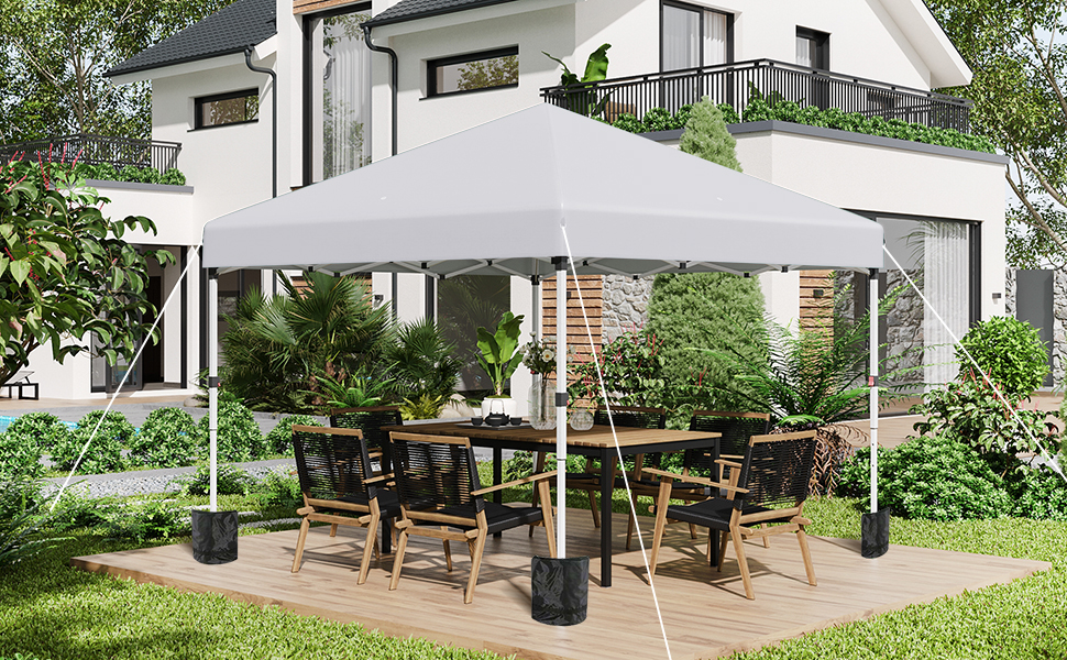 Terrasse extérieure avec deux grands parasols blancs ombrageant les ensembles de meubles de salle à manger en bois. Maison blanche moderne avec balcons visibles en arrière-plan, entourée d'un jardin paysager.
