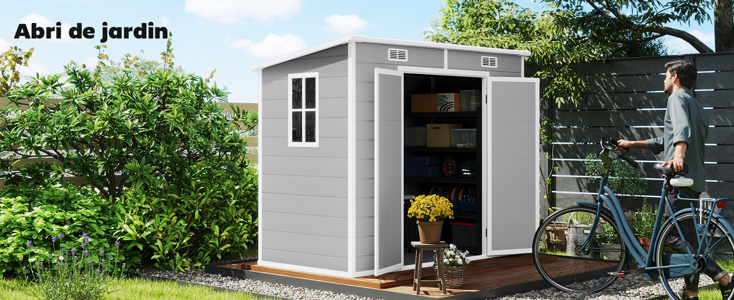 Abri de jardin gris moderne avec porte simple, fenêtre et toit incliné. Vélo et plantes en pot visibles près de l'entrée