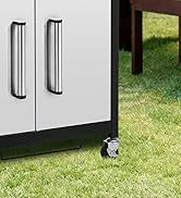 Poignées d'armoire en acier inoxydable montées sur des portes d'armoires blanches, illustrées près du niveau du sol avec de l'herbe visible à travers l'ouverture ci-dessous.
