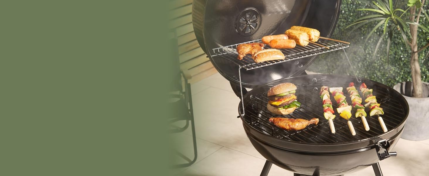 en cours d'utilisation, cuisant divers aliments, notamment des hamburgers, des hot dogs et des brochettes. De la fumée est visible, ce qui indique une cuisson active