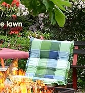 Scène extérieure avec coussin à carreaux sur un banc en bois près de fleurs éclatantes et d'un foyer, créant une atmosphère de jardin chaleureuse